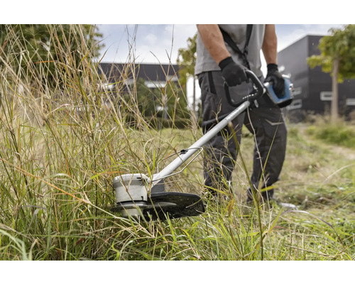 Muž strihá trávu vyžínačom.
