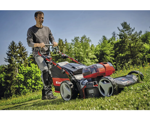 Muž tlačí akumulátorovú kosačku Einhell po trávniku.