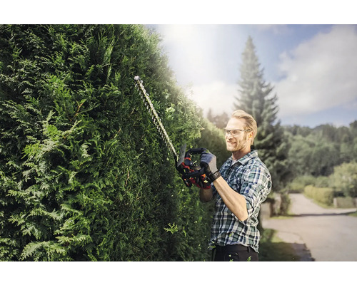 Muž strihá živý plot pomocou nožníc na živý plot