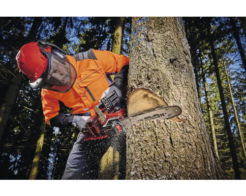 Muž v ochrannom odeve rúbe strom motorovou pílou