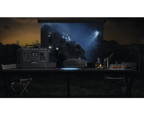 Vonkajšia scéna s napájacou stanicou Bluetti, projektorom a plátnom na stole