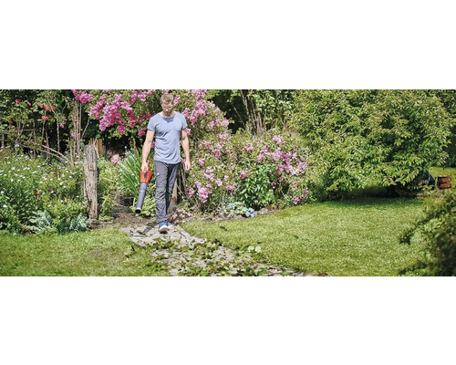 Muž používa fúkač lístia v záhrade.