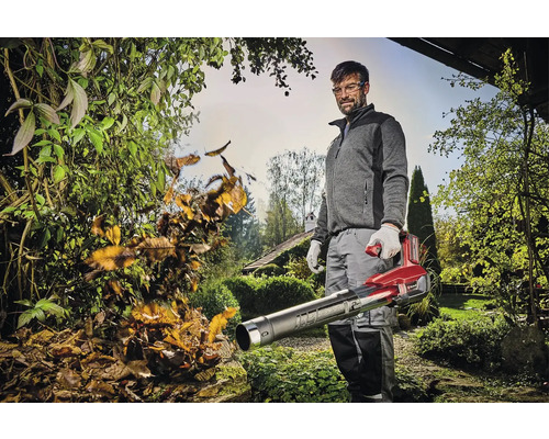Muž v záhrade odstraňuje lístie pomocou akumulátorového fúkača lístia