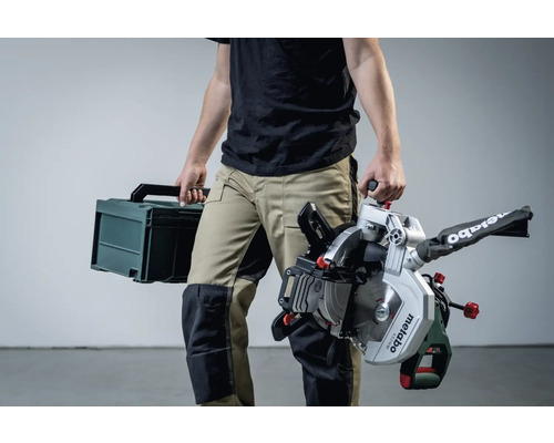 Osoba nesie pokosovú pílu Metabo a kufrík na náradie.