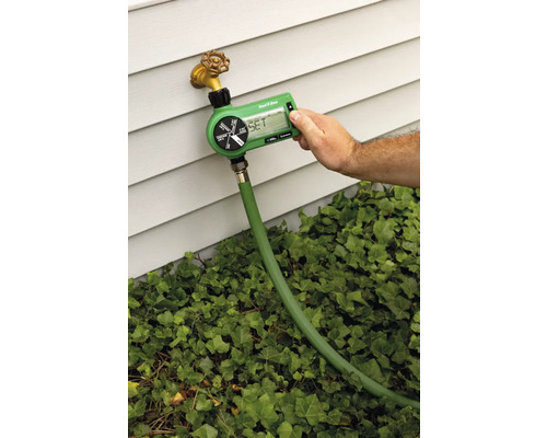 Záhradný zavlažovací počítač pripojený k vodovodnému kohútiku s hadicou, zavlažovanie nastavuje osoba.