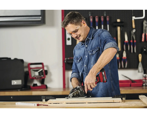 Muž pracuje s akumulátorovou ručnou okružnou pílou na kuse dreva