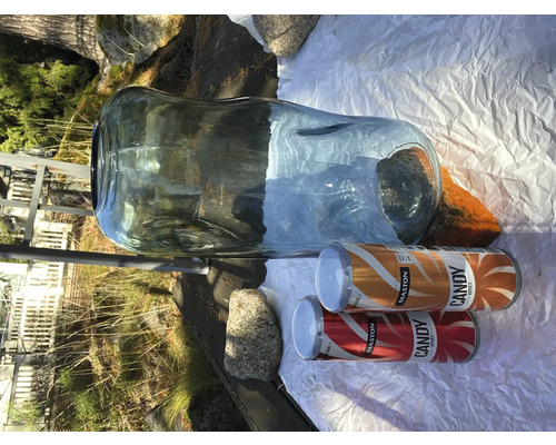 Veľká sklenená váza s dvoma plechovkami farebného spreja