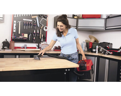 Žena čistí pracovný stôl mokrým a suchým vysávačom v dielni.