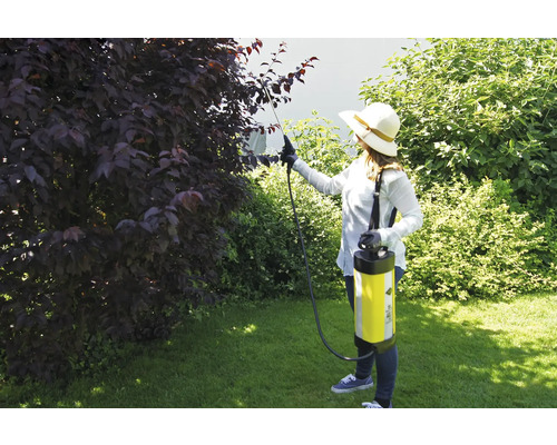 Žena používa záhradný postrekovač na ničenie škodcov v záhrade.