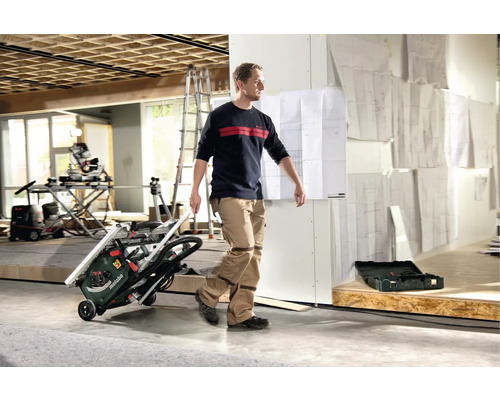 Muž prepravuje stolnú okružnú pílu Metabo v interiéri.