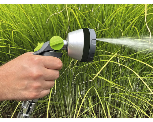 Ruka drží striekaciu pištoľ na zavlažovanie rastlín