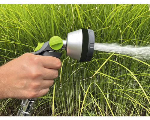 Ruka drží záhradný postrekovač, ktorý strieka vodu.