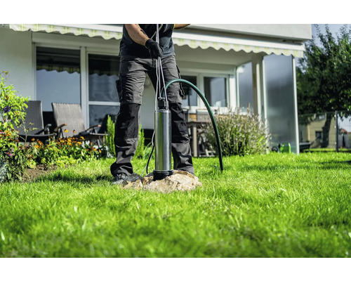 Muž inštaluje hlboké studňové čerpadlo v záhrade.