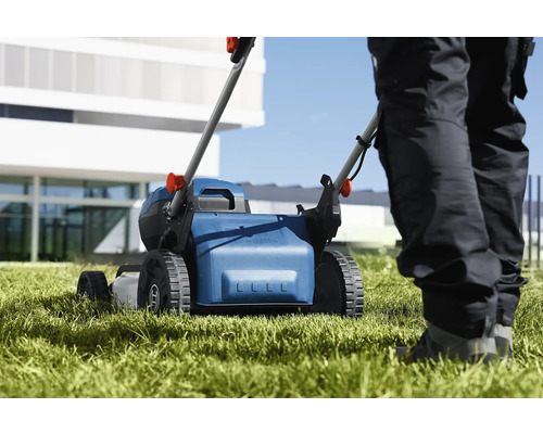 Kosačka na trávu pri práci na trávniku.