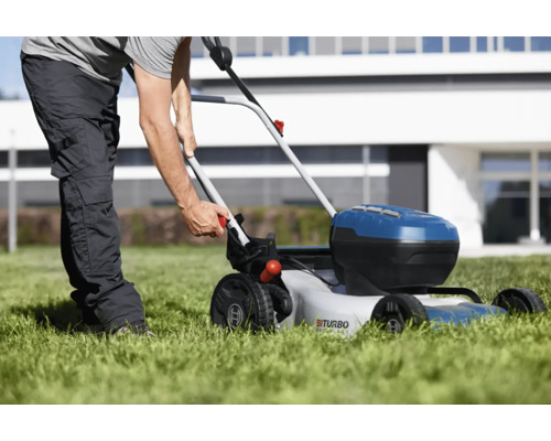 Osoba používa akumulátorovú kosačku na trávu na trávniku pred domom.