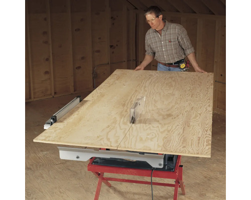 Muž reže drevenú dosku stolovou pílou.