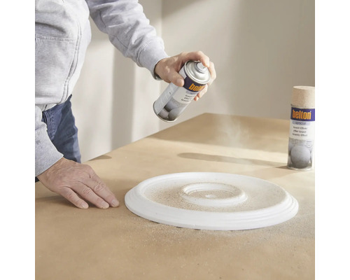 Osoba strieka farbu na rozetu pomocou spreja so žulovým efektom