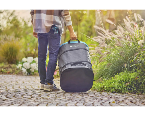 Osoba nesie záhradný vak Gardena v záhrade.