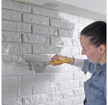 Žena natiera tehlovú stenu štetcom