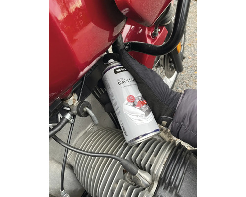Osoba používa plechovku Auto Quick Start spreja na motorku.