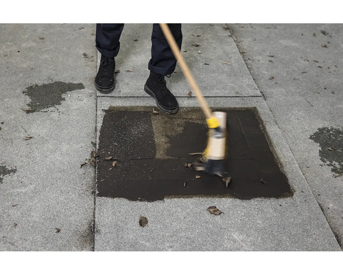 Osoba čistí sivý kamenný povrch metlou