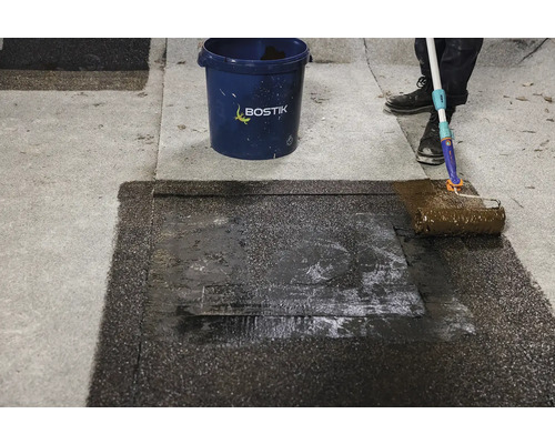 Aplikácia strešnej krytiny valčekom vedľa vedra Bostik.