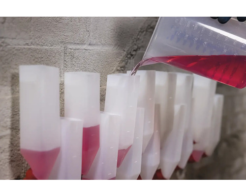 Nalievanie červenej tekutiny z odmerky do radu dávkovacích zásobníkov