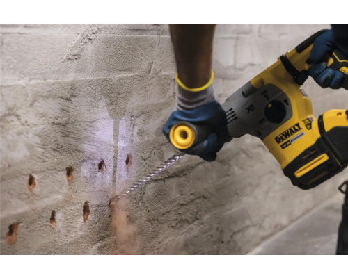 Remeselník vŕta diery do betónovej steny pomocou vŕtacieho kladiva