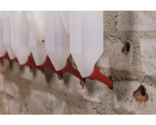 Rad nádob na kvapaliny s hadicovou prípojkou na betónovej stene