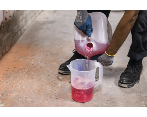 Osoba nalieva tekutinu z nádoby do odmerky.