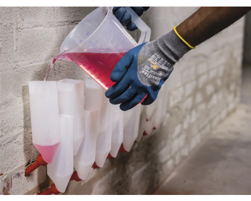 Osoba nalieva tekutinu z odmerky do radu lievikov pripevnených k stene.