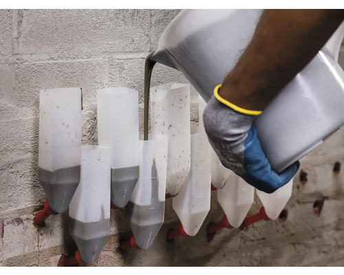 Robotník nalieva maltu do malty na tehlovej stene