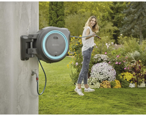 Nástenný box na hadicu Gardena so ženou polievajúcou záhradu