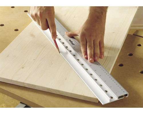 Osoba, ktorá ceruzkou kreslí čiaru pozdĺž pravítka Wolfcraft na drevenú dosku