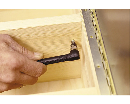 Ruka skrutkuje skrutku do dreva pomocou uhlového nadstavca