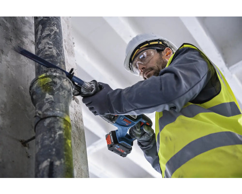 Muž reže rúru akumulátorovou šabľovou pílou.