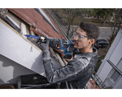 Muž pracuje s chvostovou pílou na streche