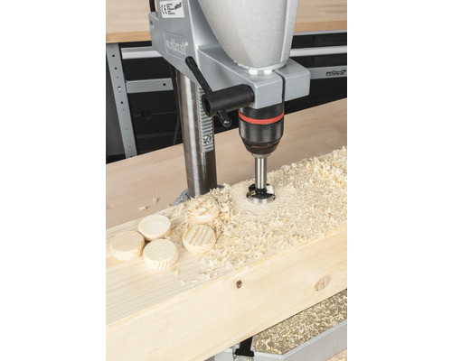 Stojanová vŕtačka vŕta otvor do drevenej dosky s drevenými kolíkmi