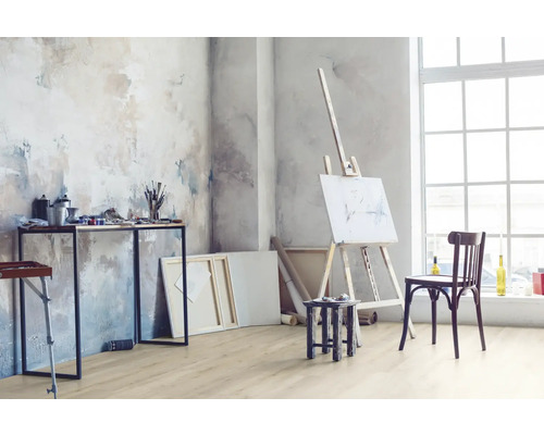 Svetlá izba s maliarskym stojanom, stolom s maliarskymi potrebami a drevenou podlahou