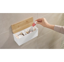 Nástenný úložný box s kozmetikou a rukou, ktorá do neho vkladá lak na nechty