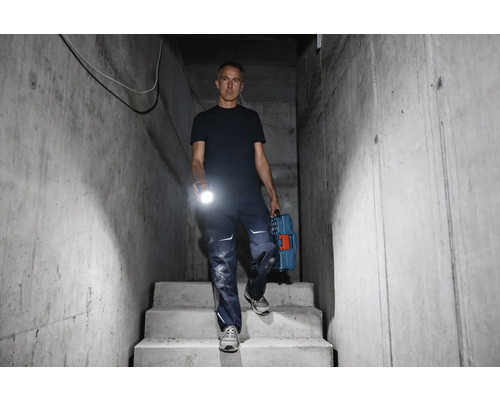 Muž schádza po betónových schodoch s baterkou a kufríkom na náradie