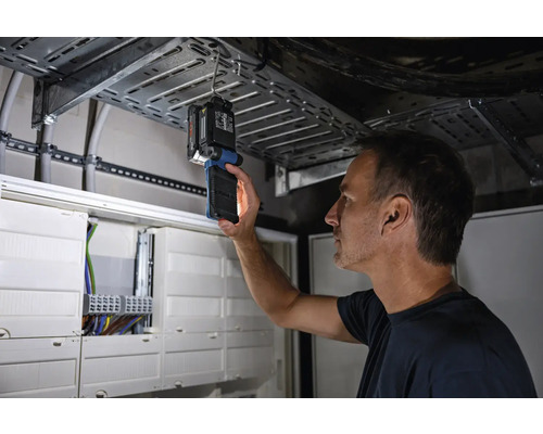 Muž kontroluje elektroinštaláciu pomocou inšpekčnej lampy.