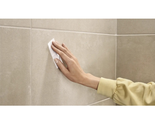 Osoba čistí dlaždice čistiacou utierkou.