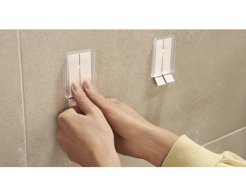 Osoba pripevňuje lepiaci háčik na stenu