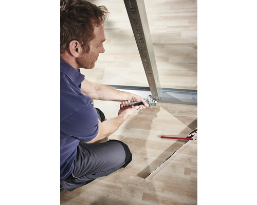 Muž upevňuje kovový profil pomocou klieští v suchej stavbe