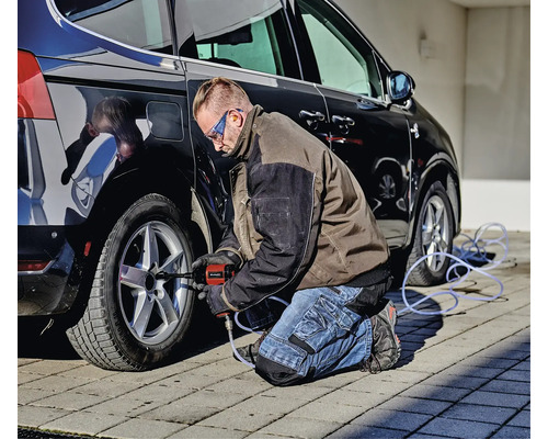 Muž používa rázový uťahovák na pneumatiku auta