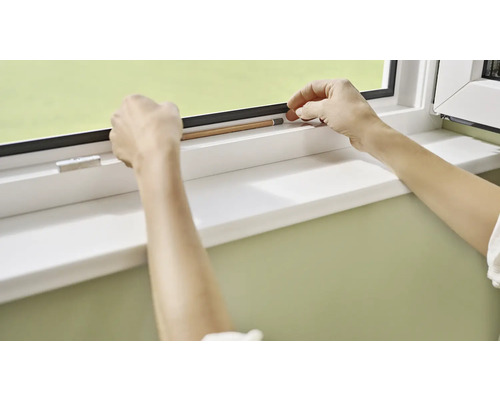 Osoba meria okno ceruzkou.