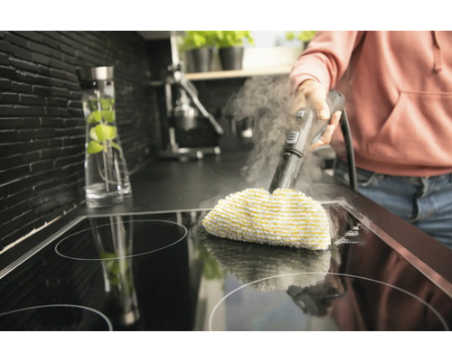 Parný čistič v prevádzke na varnej doske v kuchyni.