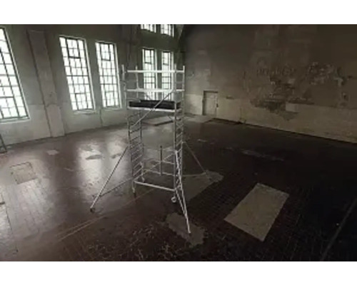 Lešenie v prázdnej miestnosti s veľkými oknami pre stavebné práce.