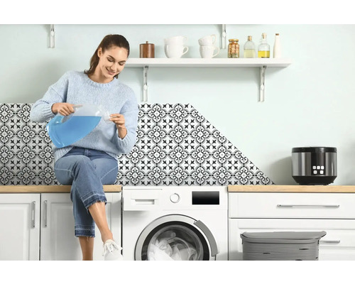 Žena sedí na práčke a nalieva tekutinu z džbánu do odmerky